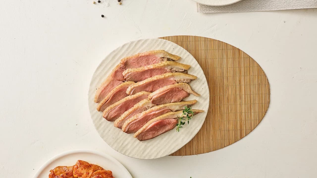 도마 위 훈제오리와 양념육 접시들을 차린 밝고 깔끔한 식탁 상차림