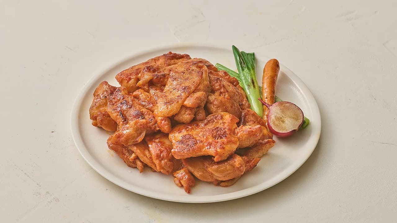 흰 접시에 푸짐하게 담긴 양념 닭다리살과 대파·고추