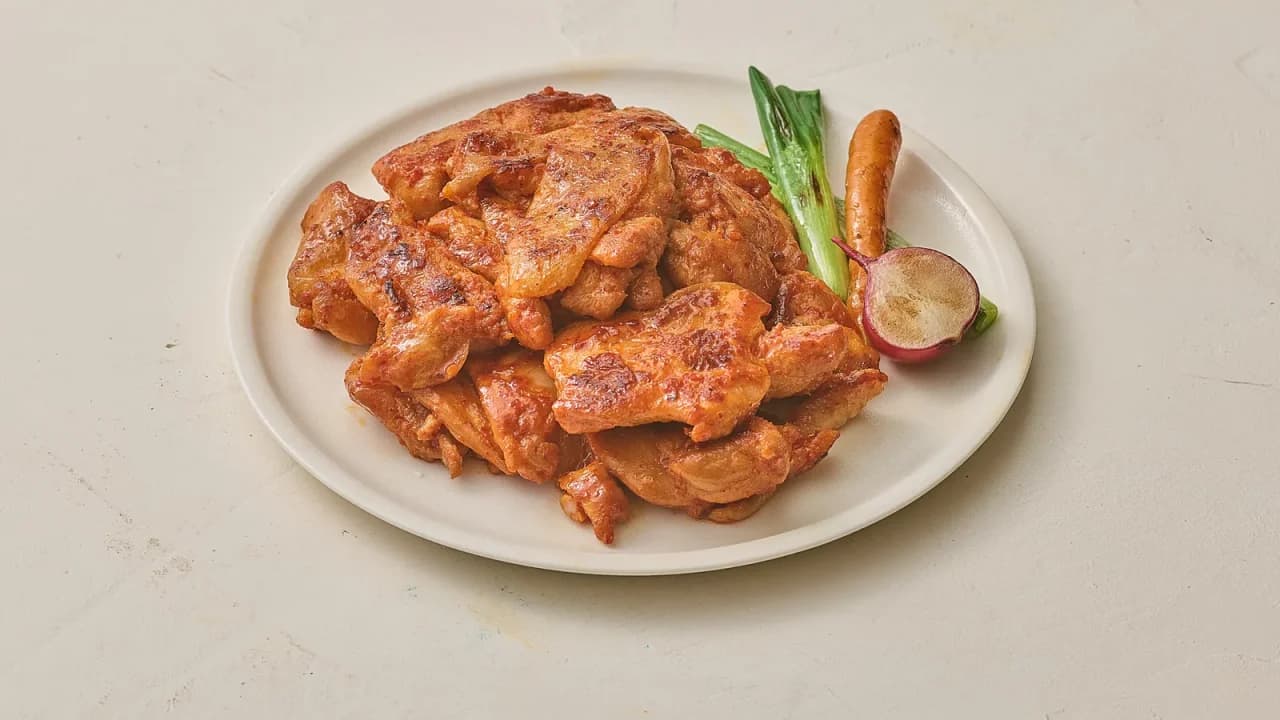 흰 접시에 담긴 양념 닭다리살 요리